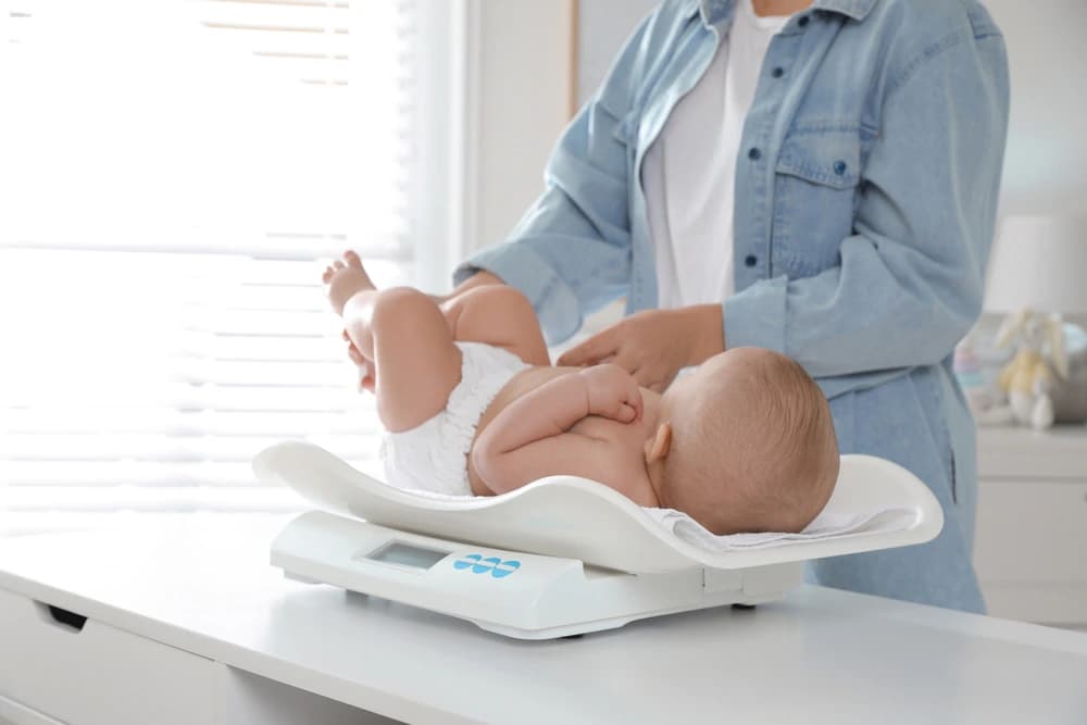 doktor boy ve kilo gelişimi takibi için bebeğin kilosunu tartıyor