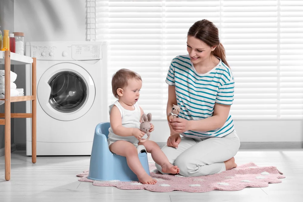 tuvalet eğitimi sürecinde lazımlıkta oturan bebek ve yanında destek olan anne
