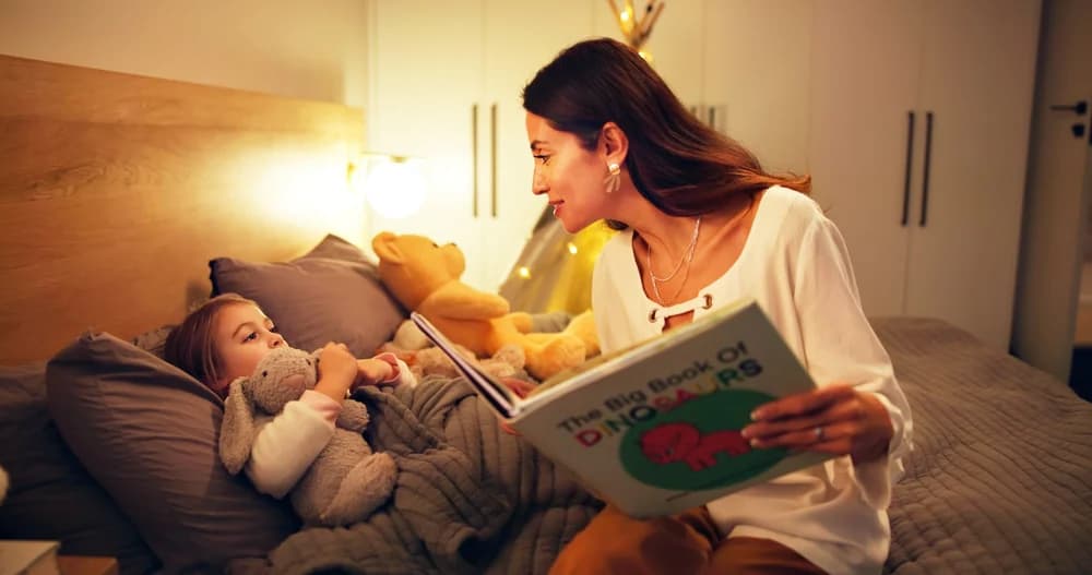 Anne yatmadan önce kucağındaki kitabı küçük çocuğuna okuyor — çocuklar için doğru kitap seçimi